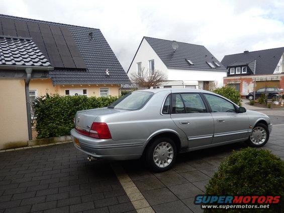 Silver sedan parked on a paved driveway, showing its side and rear