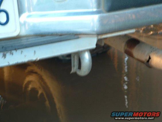 Rear bumper with a silver tow hook and a rusted exhaust pipe