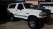 1992 Ford Bronco - This lifted 1992 Ford Bronco is parked in front of a garage with a utility truck in the background.