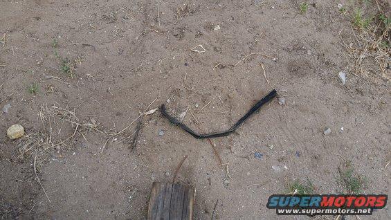 Black rubber trim piece on dirt ground with Supermotors logo