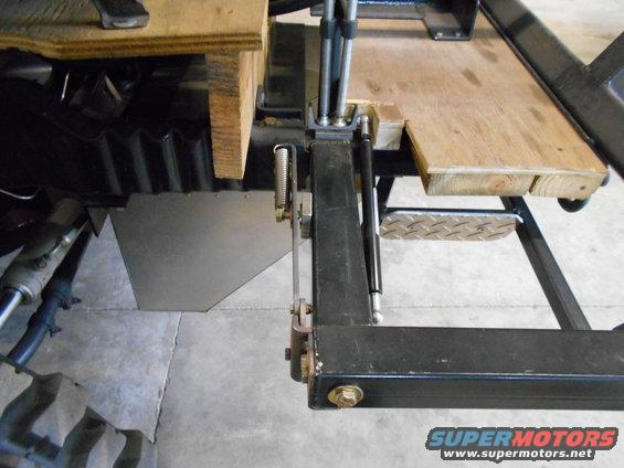 Vehicle chassis with wooden platform, metal shielding, and tire visible