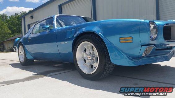 Blue 1970 Pontiac Trans Am coupe with white wheels parked in front of a garage