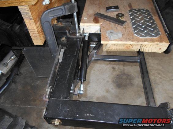 metal bracket clamped to wood, with small metal pieces and diamond plate on top