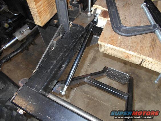 Close-up of vehicle frame or suspension part held by clamps and wood blocks