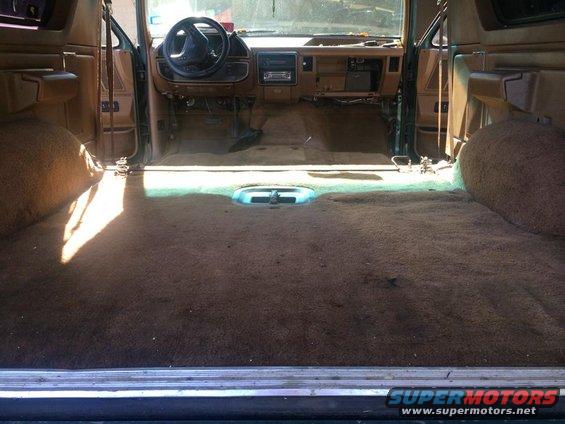 Interior of a vehicle with carpeted floor and dashboard visible. Looks like it's being worked on