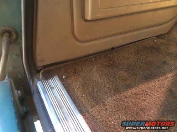 Close-up of a vehicle's interior door sill and brown carpet