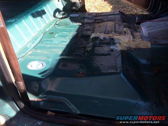 Green interior floor of a vehicle with exposed metal and some insulation material