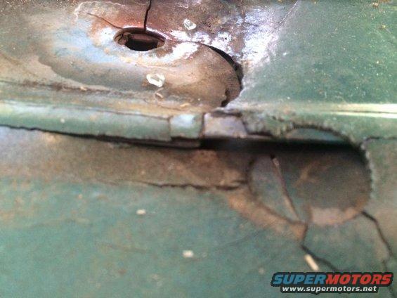 rusted green metal panel with a hole and cracks