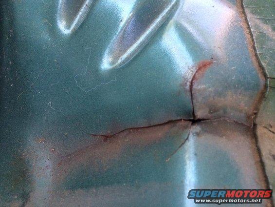Close-up of a teal metal panel with a crack and some rust showing