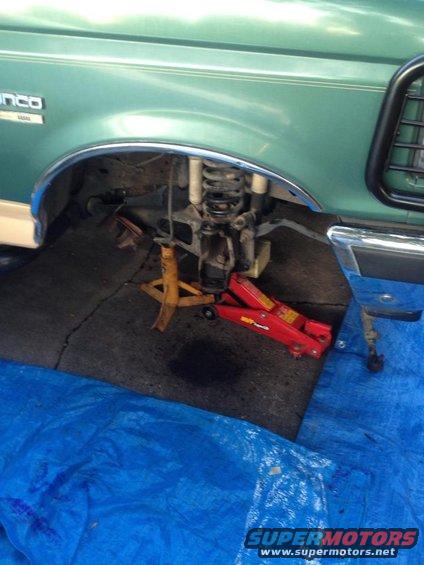 Green 1990 Ford Bronco front fender and suspension on jack stands