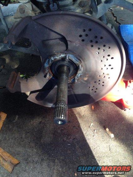 Close-up of a damaged brake rotor and axle assembly on the ground