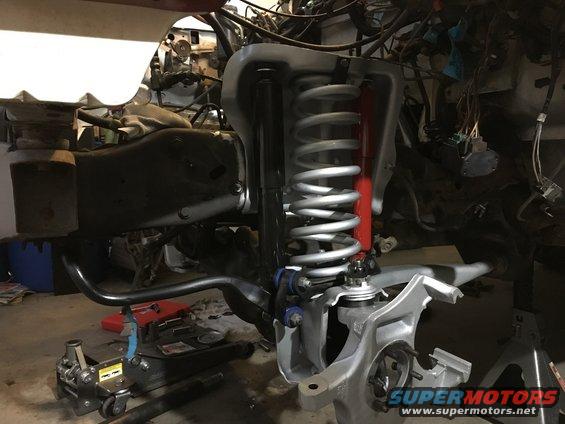 Vehicle suspension components with coil spring and shock absorber, engine bay wiring visible
