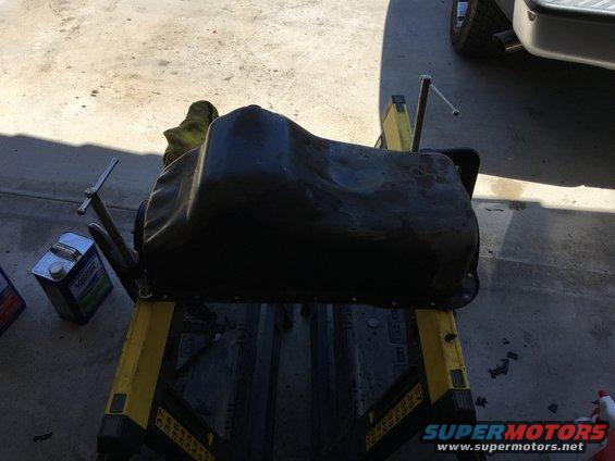 Black oil pan on a yellow stand with a can of oil nearby