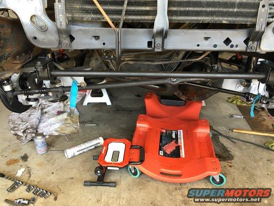 Undercarriage of a vehicle with steering linkage, radiator, and a creeper on the ground
