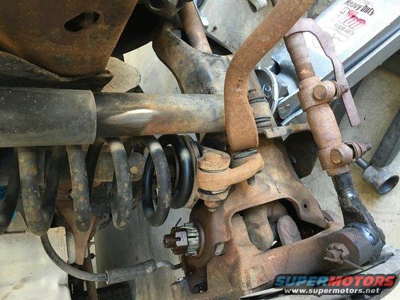 Close-up of rusted suspension components and a coil spring, likely from a truck or SUV