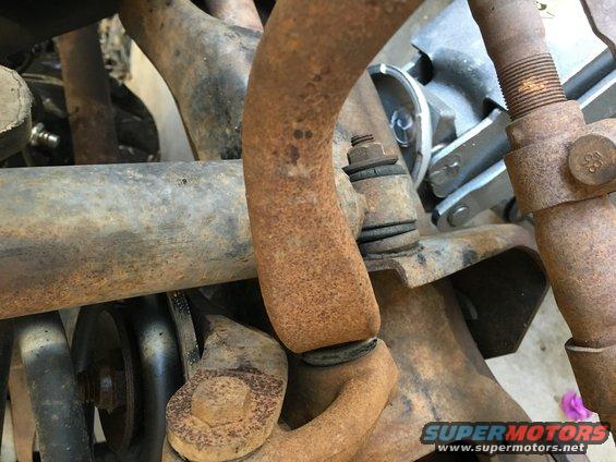 Close-up of rusty suspension parts, including a sway bar and ball joint