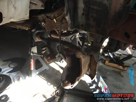 Underside of a vehicle on jack stands, showing suspension parts and frame