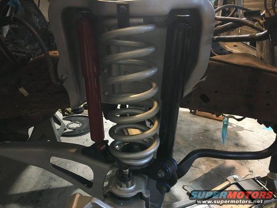 Front suspension assembly with silver coil springs and red/black shock absorbers