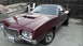 1972 Ford Ranchero - A 1972 Ford Ranchero in a deep maroon color is parked in a driveway, prominent hood scoops and classic aftermarket wheels.