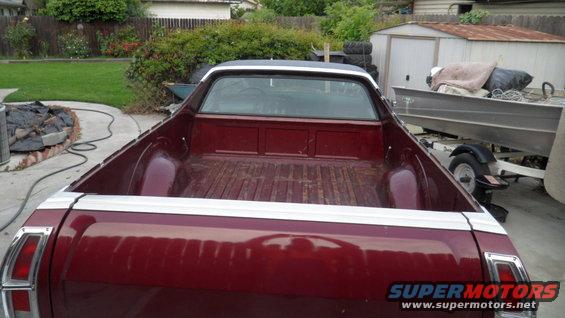 red pickup truck bed with white trim, boat on trailer in background