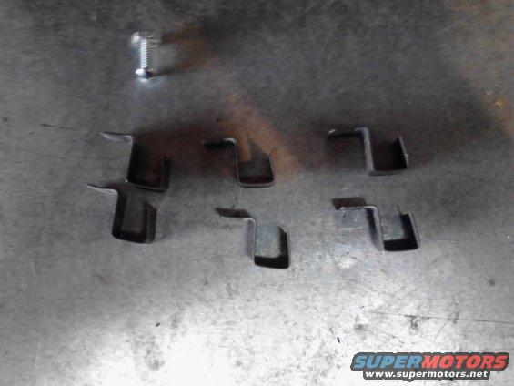 Metal clips and a screw on a textured surface