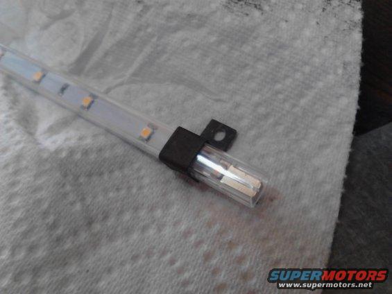 LED strip light with orange LEDs and a clear plastic cover, attached to a black mounting bracket