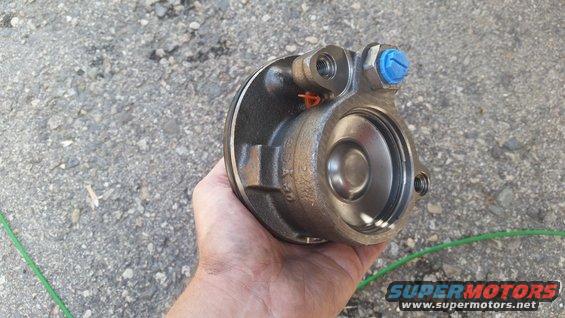 Brake caliper part held in hand, showing internal piston and blue cap