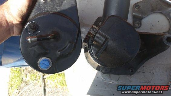 Two black power steering pumps side-by-side, one held by a hand