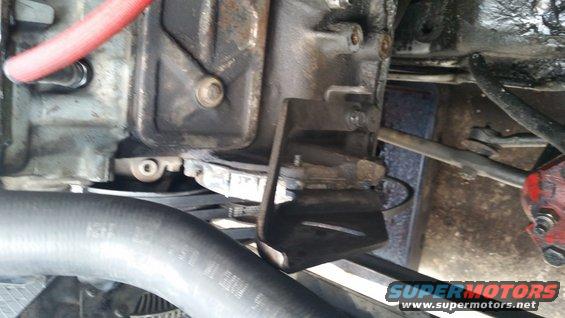 Close-up of engine block, transmission housing, hoses, and mounting bracket