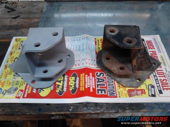 One gray metal bracket and one rusty black metal bracket on a liquidation sale newspaper