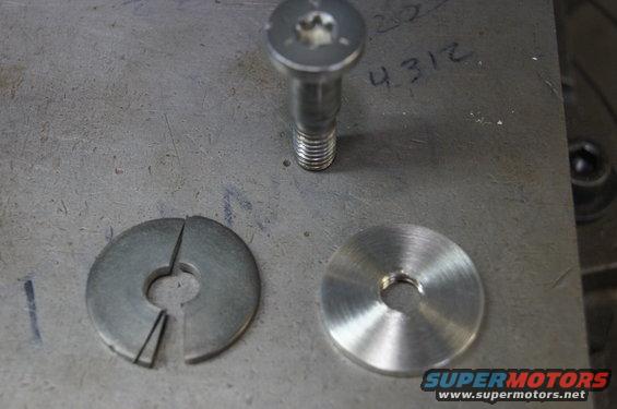 Bolt and two washers, one split, on a metal surface with handwritten numbers