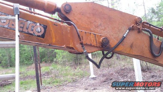 Excavator arm with hydraulic line and Kobelco logo