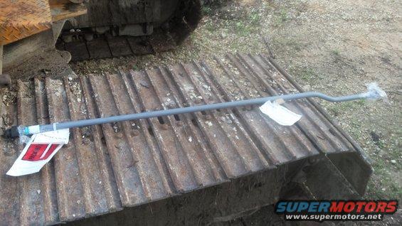 Gray hydraulic line with red and white tags on a rusty metal track