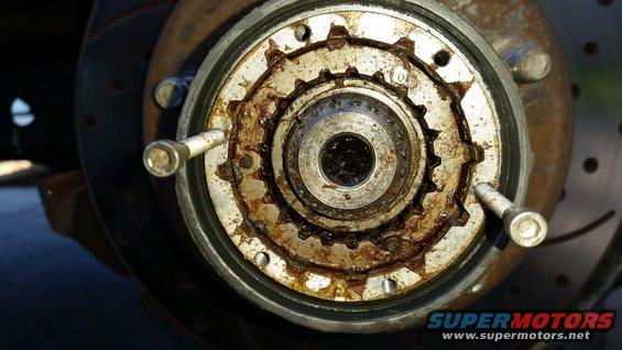 Rusty manual locking hub with visible gear teeth and bolts