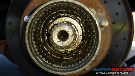 close-up of a greasy, toothed locking hub assembly with a brake rotor visible behind it
