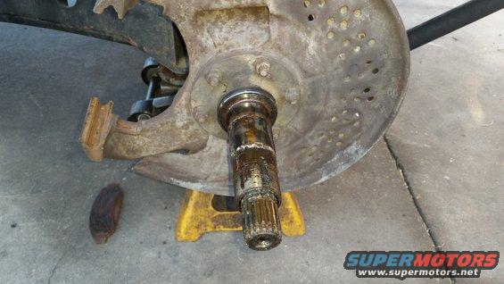 close-up of a rusty wheel hub assembly on a jack stand, part of a vehicle's suspension