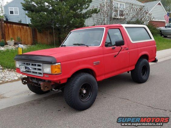 Red 1988 Ford Bronco with white top parked on street