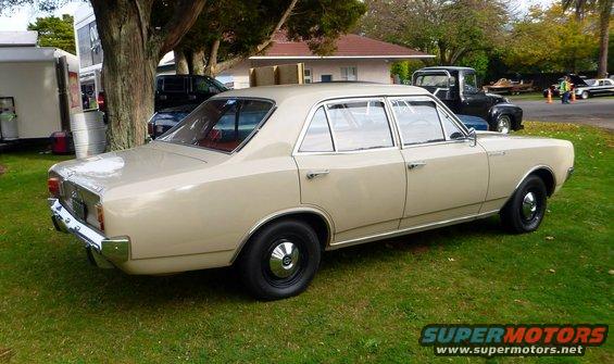 Tan sedan parked on grass, rear quarter view