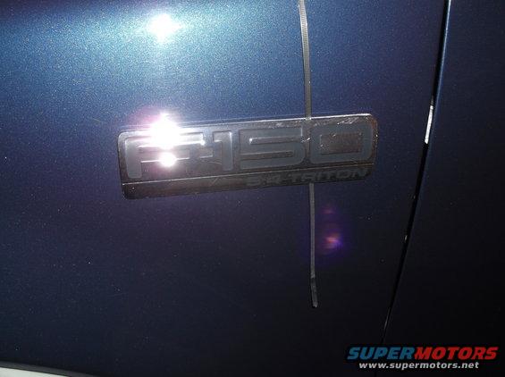 Close-up of F-150 5.4 Triton badge on dark blue vehicle body