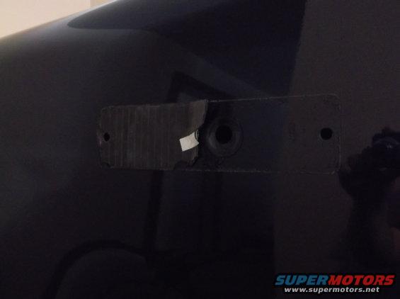 Black Ford F-150 rear bumper mounting bracket with torn tape and a hole