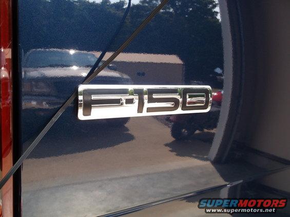 Chrome F-150 emblem on the side of a dark blue 2005 Ford F-150 truck
