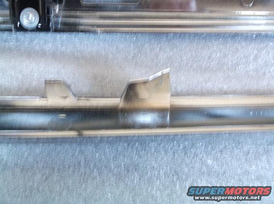 Close-up of a chrome trim piece with a mounting tab and some faint markings