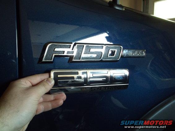 Hand holding a Ford F-150 emblem over the F-150 FX4 emblem already on a blue truck