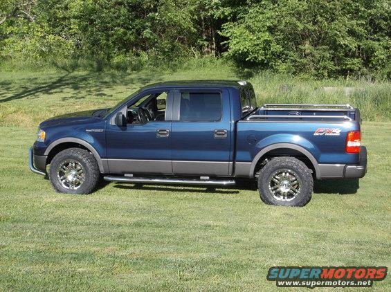 Blue Ford F-150 pickup truck with chrome wheels and running boards parked on grass