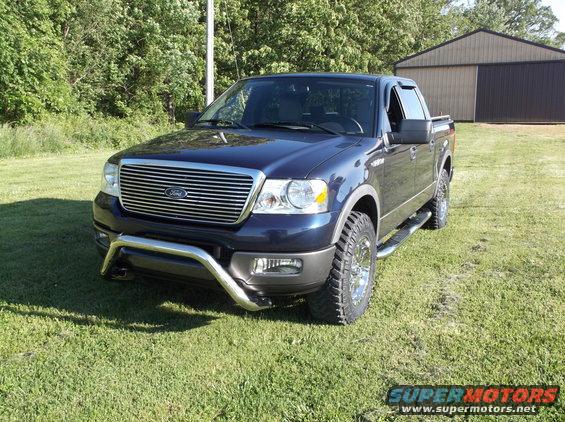 Dark blue 2005 Ford F-150 pickup truck parked on grass in front of a barn