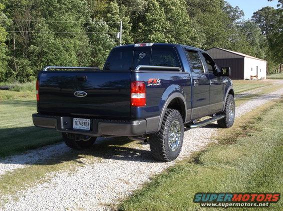 Dark blue Ford F-150 pickup truck with chrome wheels and FX4 Off Road decal, parked on a gravel driveway