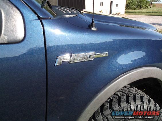 Close-up of a blue 2005 Ford F-150 fender with F-150 and 4x4 badges visible
