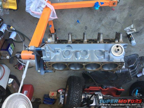 Engine block on an orange engine stand with various tools and parts around it