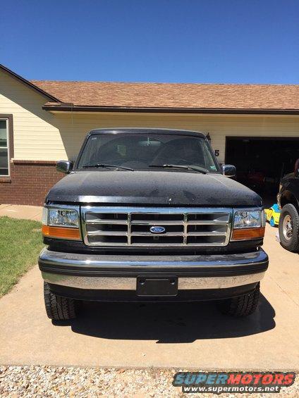 Black Ford F-Series truck parked in front of a house. Another vehicle is partially visible to the right
