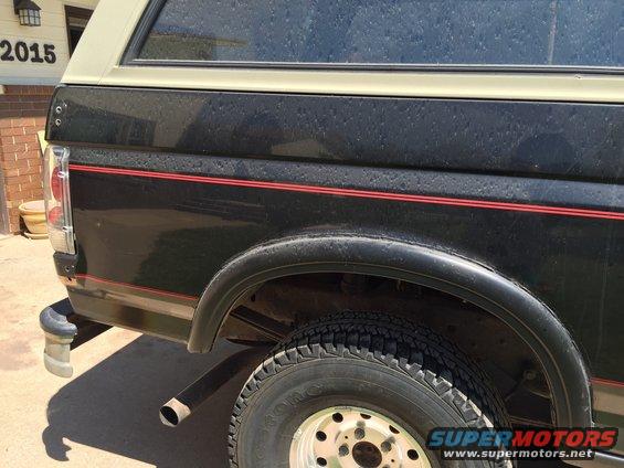Black Ford Bronco rear quarter panel with red stripe and beige camper shell